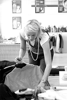 Grey scale worker looking through stack of clothes