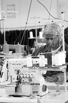 Grey scale worker lsewing in the KARMA factory