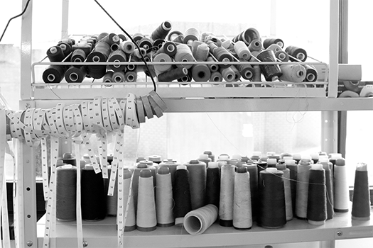 Grey scale spools of thread on a rack with tape measure