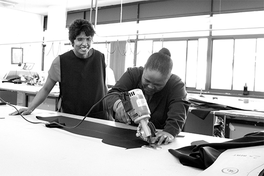 Grey scale lady cutting fabric at KARMA clothing factory