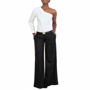 A person wearing a stylish Raven Shirt 30—a white one-shoulder long-sleeve top—and high-waisted black wide-leg pants, standing with hands in pockets against a white background.