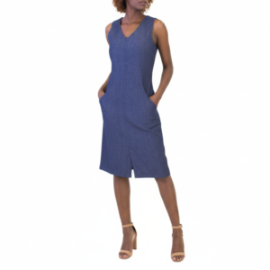 Woman standing, hands in pockets, wearing a blue sleeveless V-neck dress with front pockets and light brown heels.