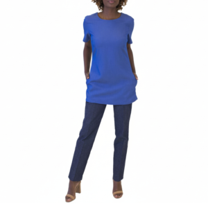 Stylish woman in a vibrant blue short-sleeved tunic, dark blue pants, and tan open-toed heels, hands in pockets.