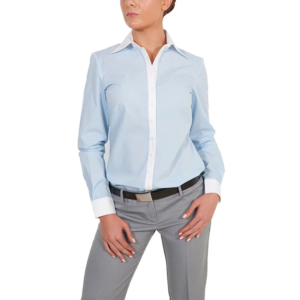 A woman wearing a light blue statement shirt with white cuffs and collar, paired with gray pants and a black belt, stands with her hands resting near her hips against a white background.