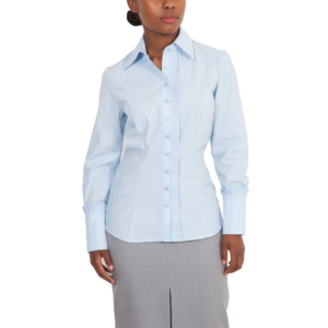 A woman wearing the Blue Domino Shirt, featuring ruffle detail along the buttons and long sleeves, is paired with a light gray skirt as she stands against a white background.