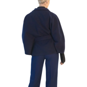 Woman in dark blue belted wrap jacket with wide sleeves and matching trousers, seen from behind.