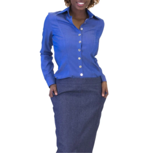 Woman in a blue button-up shirt and dark blue pencil skirt with hands in pockets, smiling.