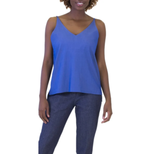 Smiling woman in a bright blue V-neck camisole and dark blue pants, posing confidently.