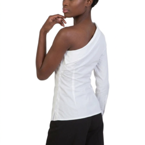 A woman wearing a white, one-shoulder long-sleeve Raven Shirt and black pants poses against a white background, her back slightly turned and one hand near her chin.