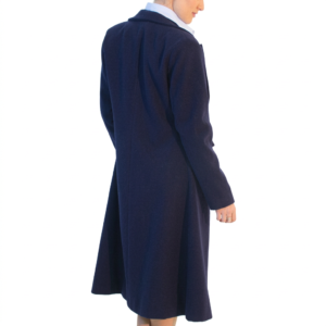 Person in a navy long coat and light blue shirt, back to viewer, head turned right, looking over shoulder.