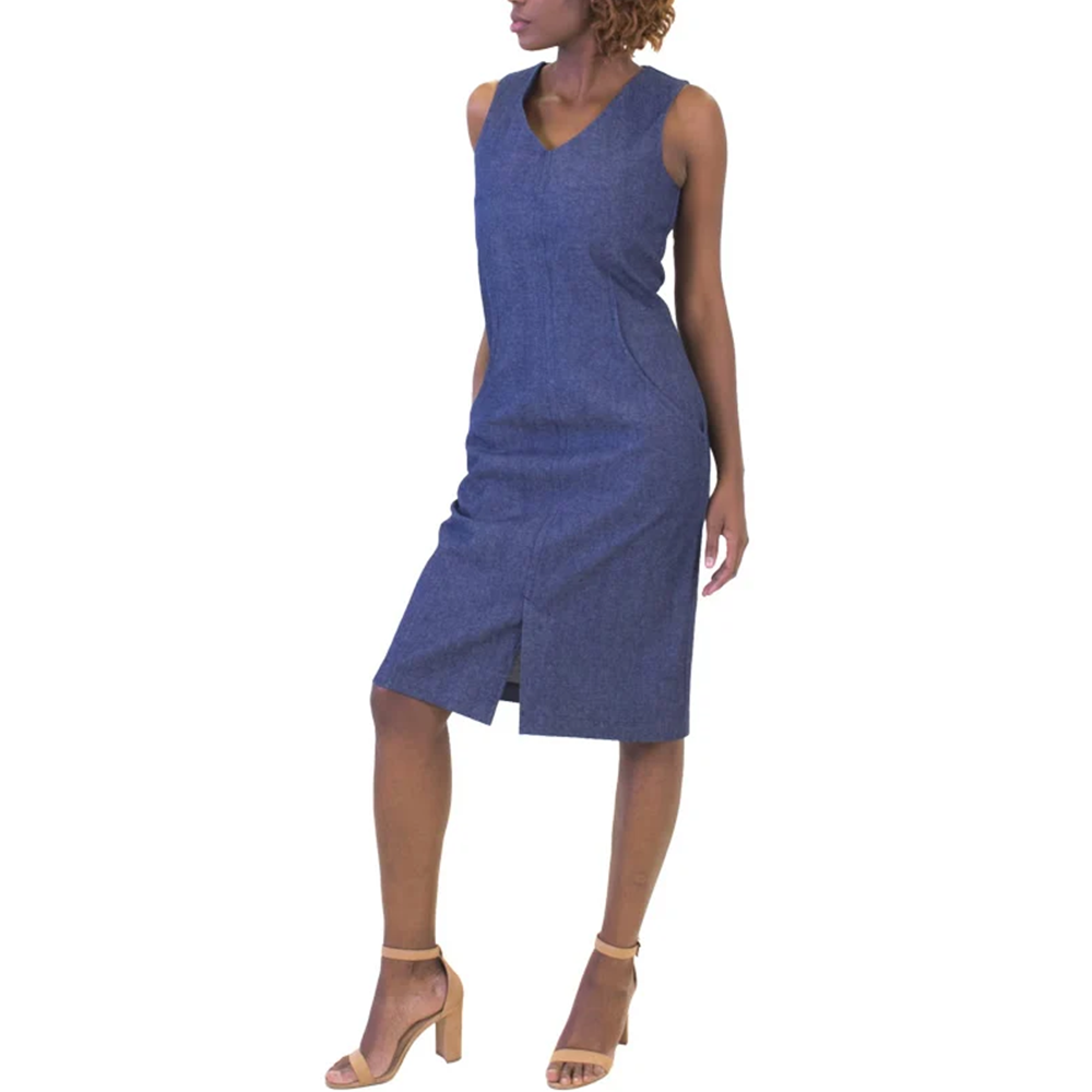 Woman standing in a sleeveless, V-neck, knee-length blue denim dress with a front slit and tan high heels.