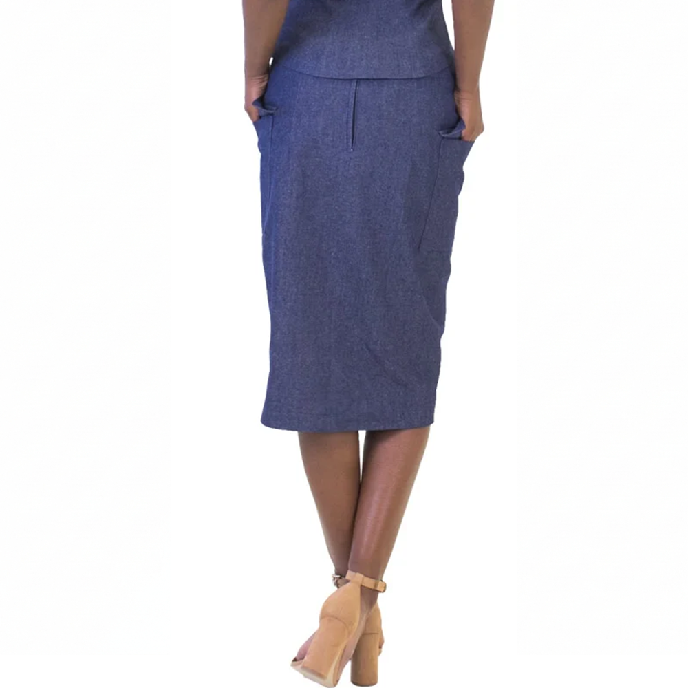 Rear view of a person in a blue pencil skirt, hands in pockets, with tan block heels. Modern business fashion.