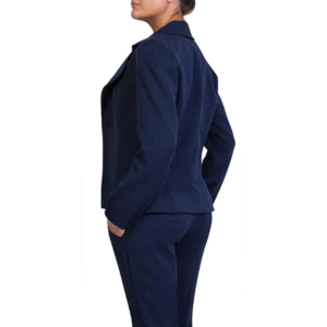 Professional woman in dark navy blue pantsuit, side profile, hands in pockets, facing left.