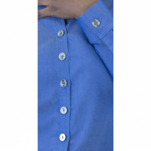 Blue dress shirt detail: button placket with silver-rimmed buttons and cuff. A hand rests on the fabric.