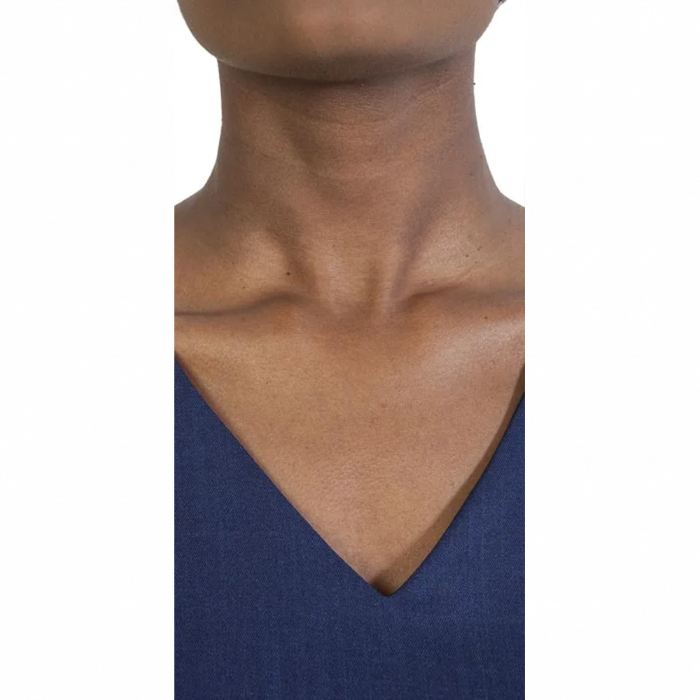 Rich dark skin tone on a person's neck and upper chest in a deep blue V-neck top.
