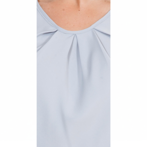 Person's upper chest and neck in a light blue-grey pleated V-neck top, with visible freckles.