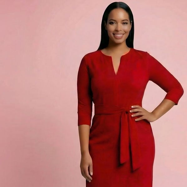 Stylish woman in a vibrant red tie-waist dress, smiling confidently, hand on hip, against a soft pink backdrop.